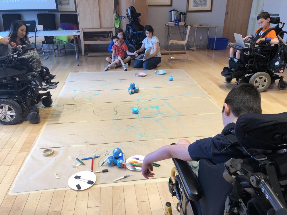 Painting on the floor with Weavly was inaccessible for some of the students using mobility devices. Floor level painting activity with children on wheelchair and facilitators